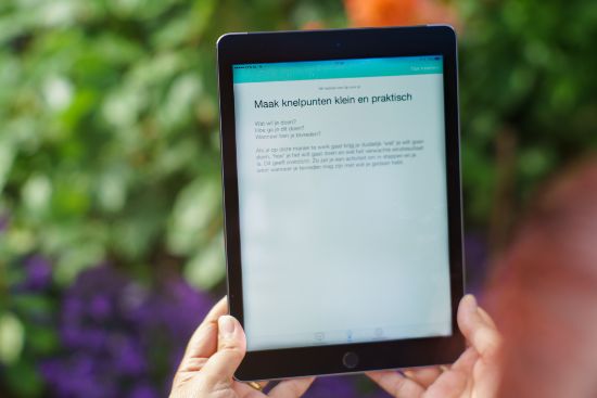 iPad in handen, op het scherm is een tip van de app I-ACT te zien over 