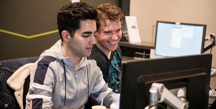 Twee jongens achter beeldscherm op werkplek HvA