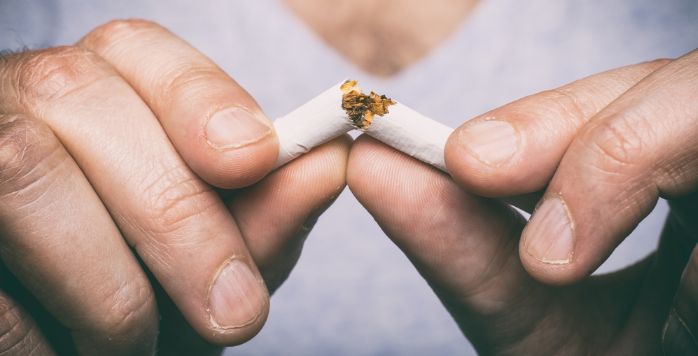Man breekt met handen sigaret in tweeën