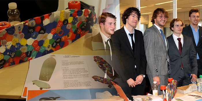 Groep studenten met skateboard gemaakt van gerecyclede plastic flessendoppen