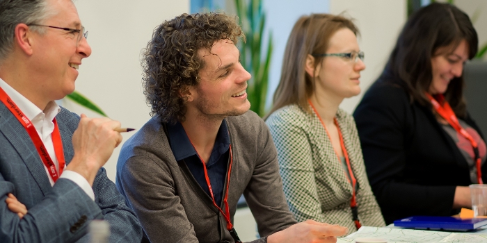Workshopdeelnemers luisteren naar spreker