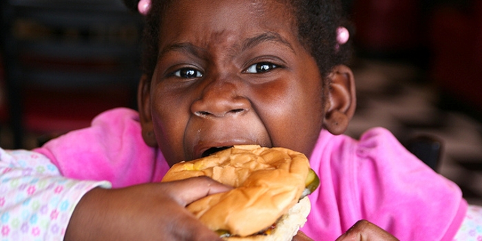 een kind neemt een hap uit een hamburger