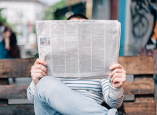 Iemand die de krant leest op een bankje