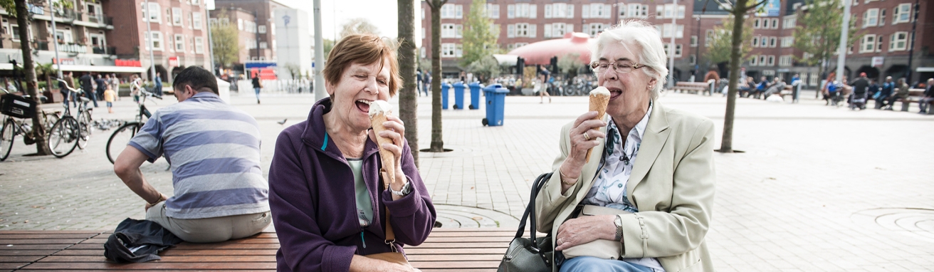 Dames op een bank eten een ijsje