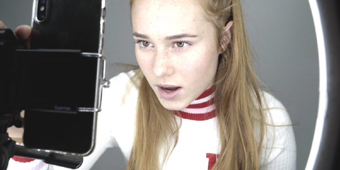Screenshot uit de film waarop de 14-jarige Leonie aan het vloggen is. Ze heeft rood haar met spotjes en praat tegen het scherm van haar telefoon.